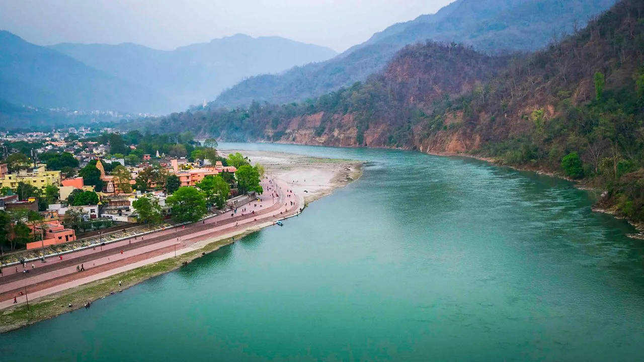 Aerial view of the turquoise Ganges river flowing through Rishikesh, India, a popular destination for planning adventure sports trips.