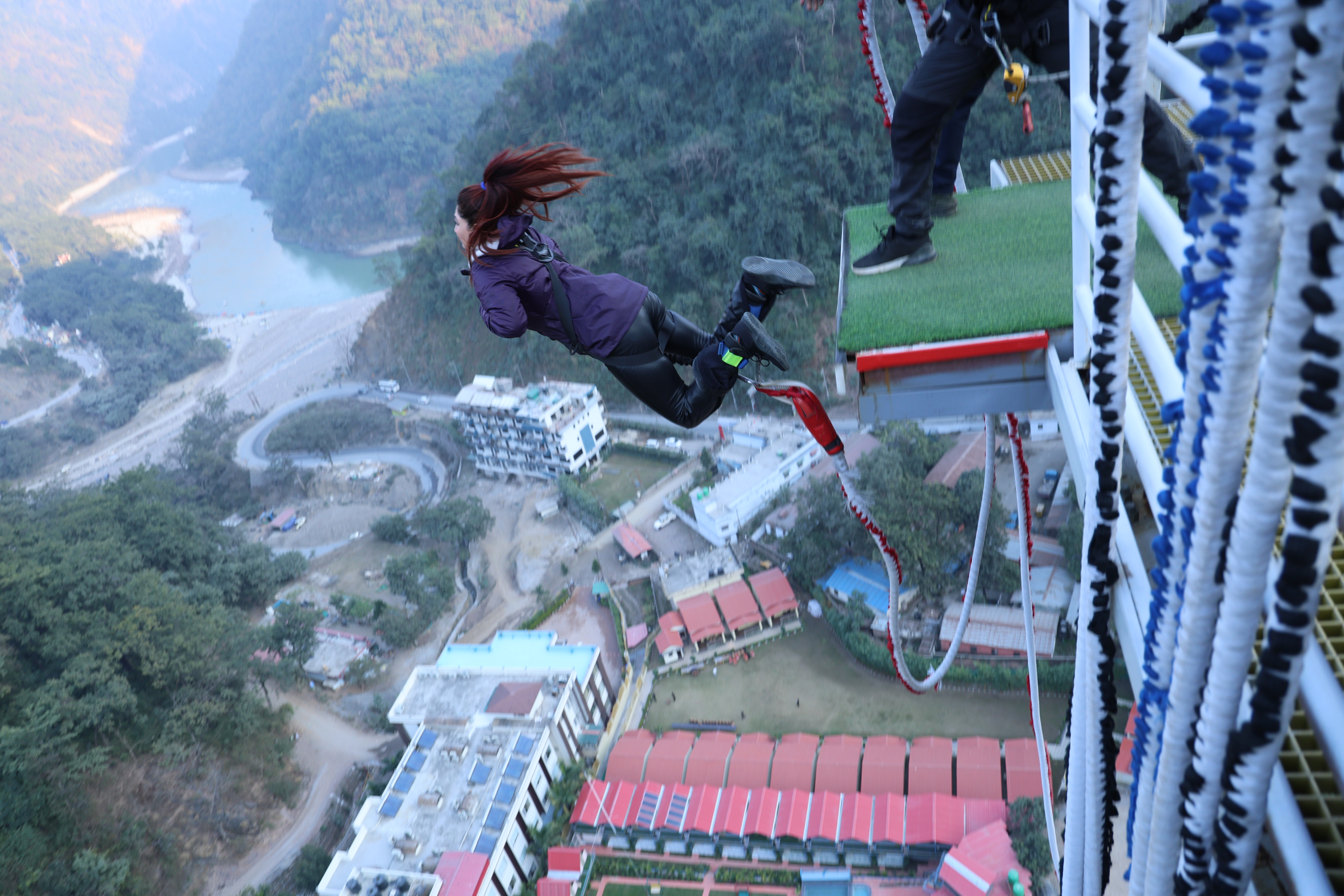 Woman bungee jumping from a high platform over a mountain valley
