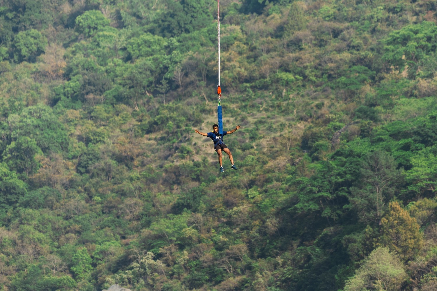 Bungee jumper suspended in mid-air over the valley in Devprayag