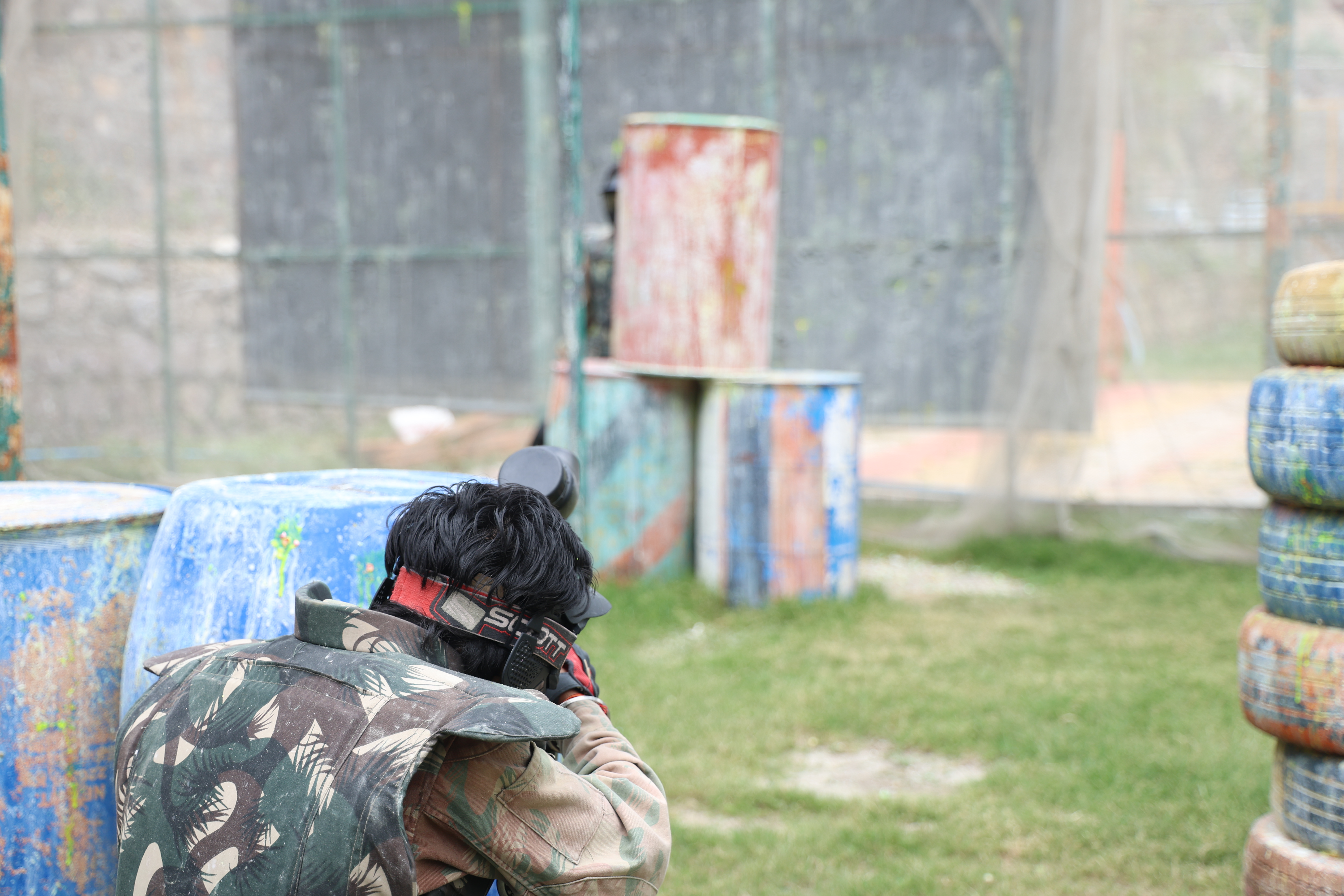 Paintball activity in Rishikesh with a player aiming a paintball marker in an outdoor arena.