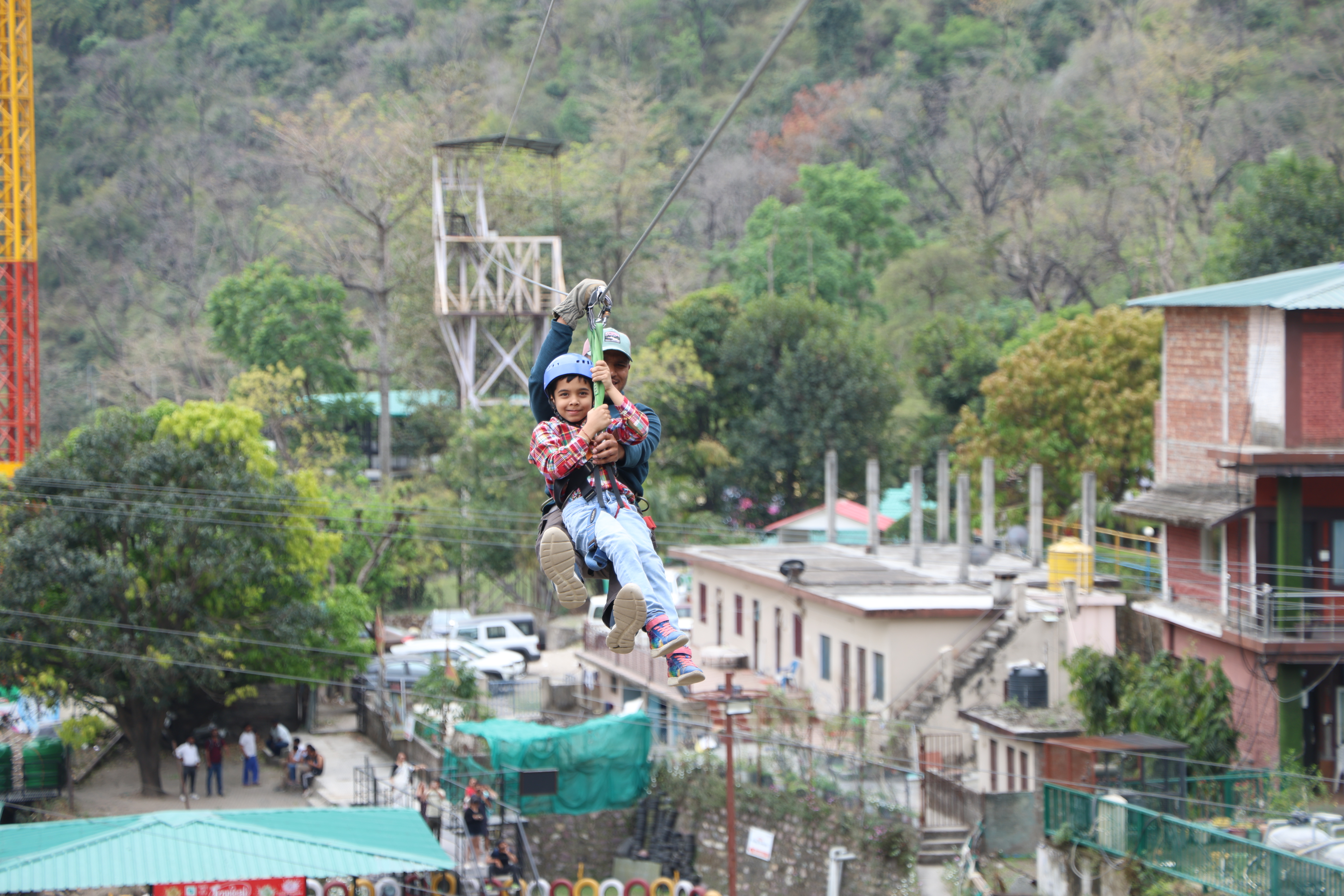 Ziplining experience in Rishikesh with a child and adult wearing safety helmets and harnesses.