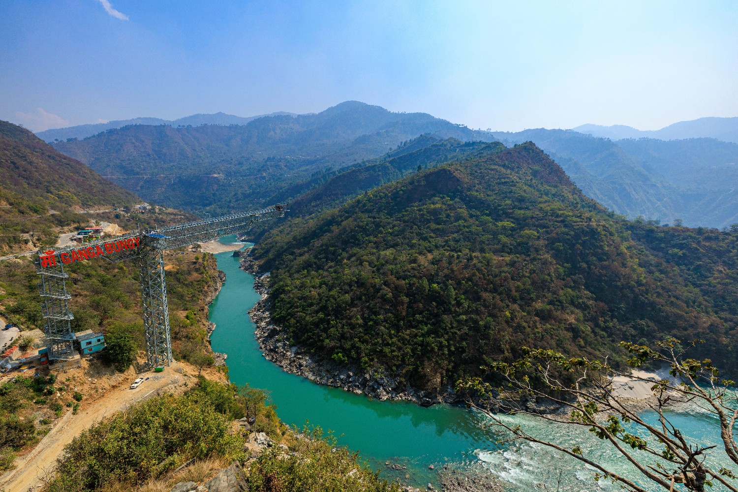Maa Ganga Bungy bridge over the turquoise river surrounded by green hills in Devprayag, Uttarakhand.