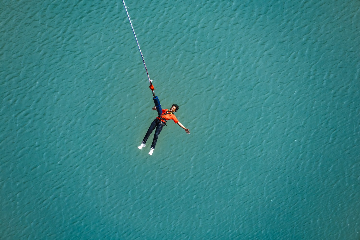 Person performing a bungee jump at Maa Ganga Bungy over turquoise water in Devprayag.