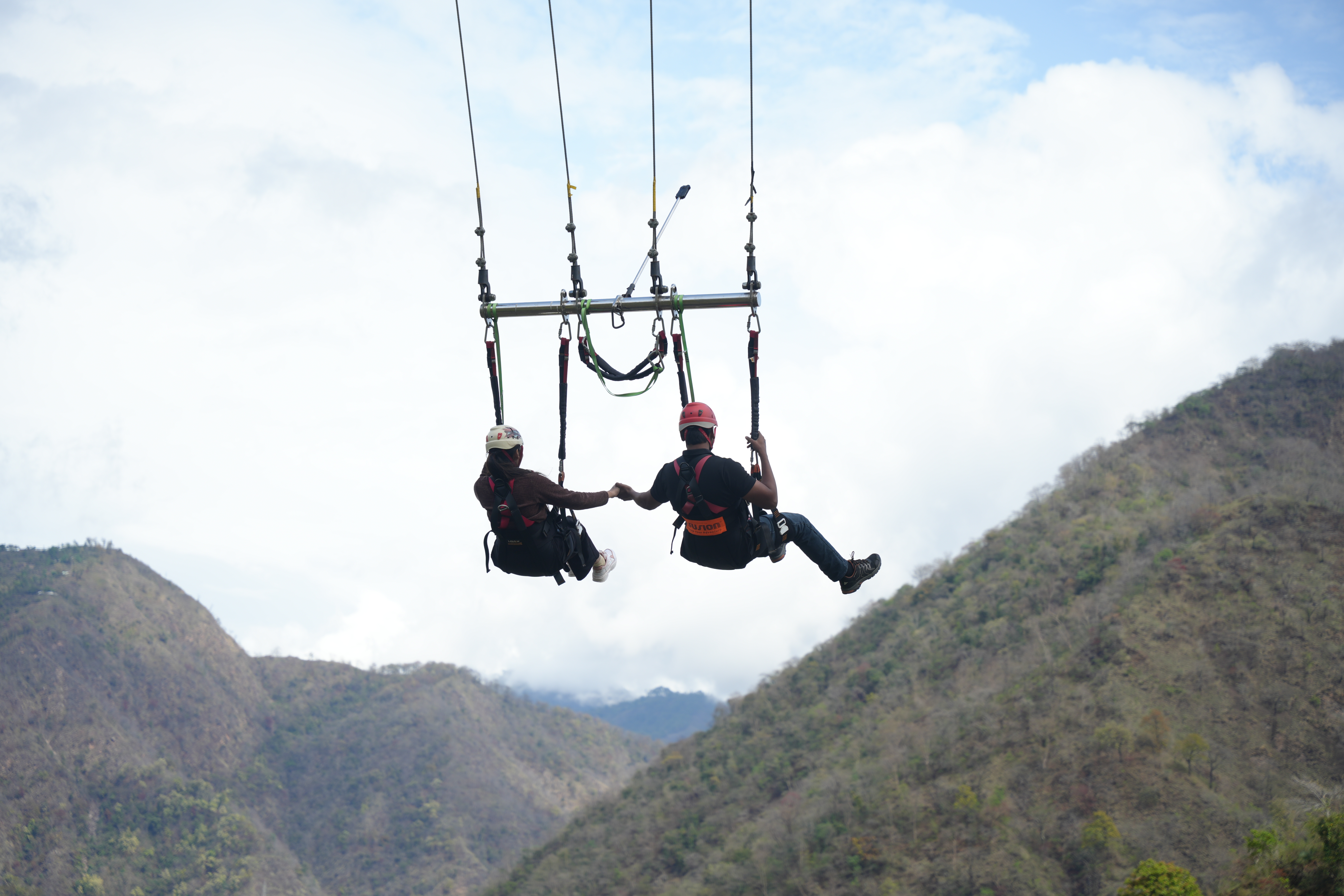 Couple enjoying a giant swing adventure over the Himalayan valley in Rishikesh.